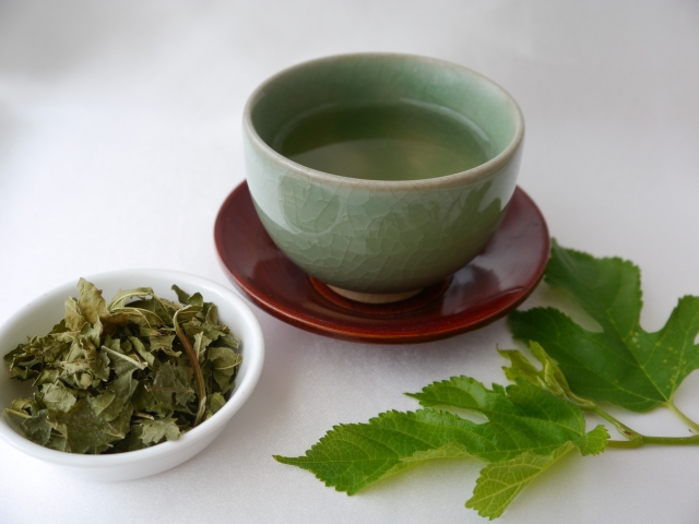 小皿に盛られた桑の葉茶の茶葉と湯吞に注がれた桑の葉茶
